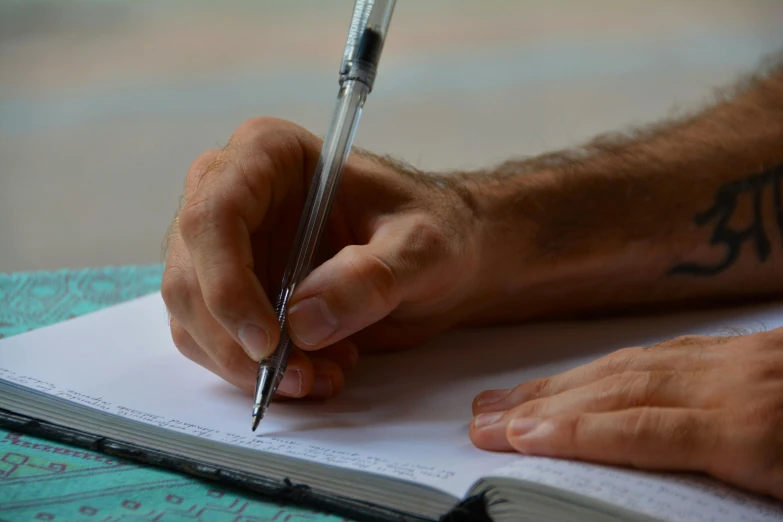 a man is writing on paper with his pen