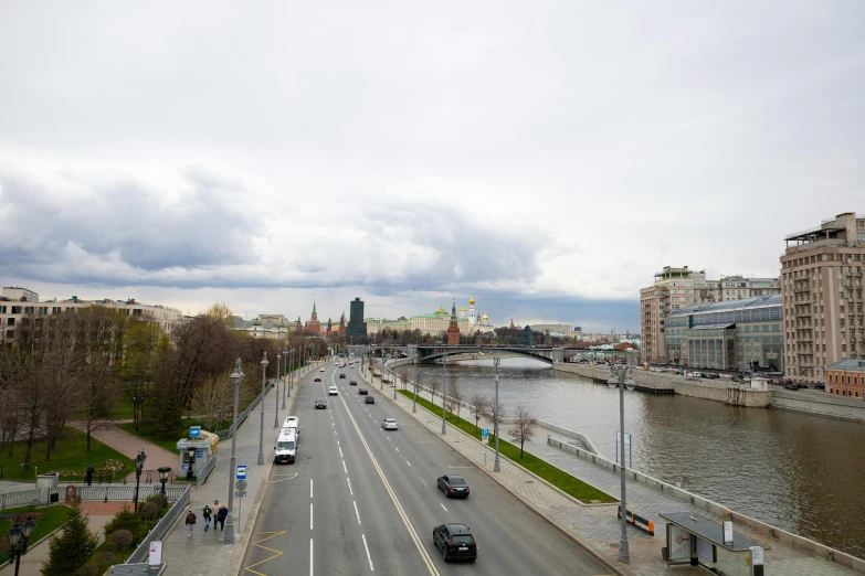 a city street filled with lots of traffic next to a river, by Serhii Vasylkivsky, pexels contest winner, socialist realism, partly cloudy day, gta in moscow, 000 — википедия, full body image