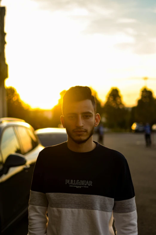 a man standing in the street next to a parked car