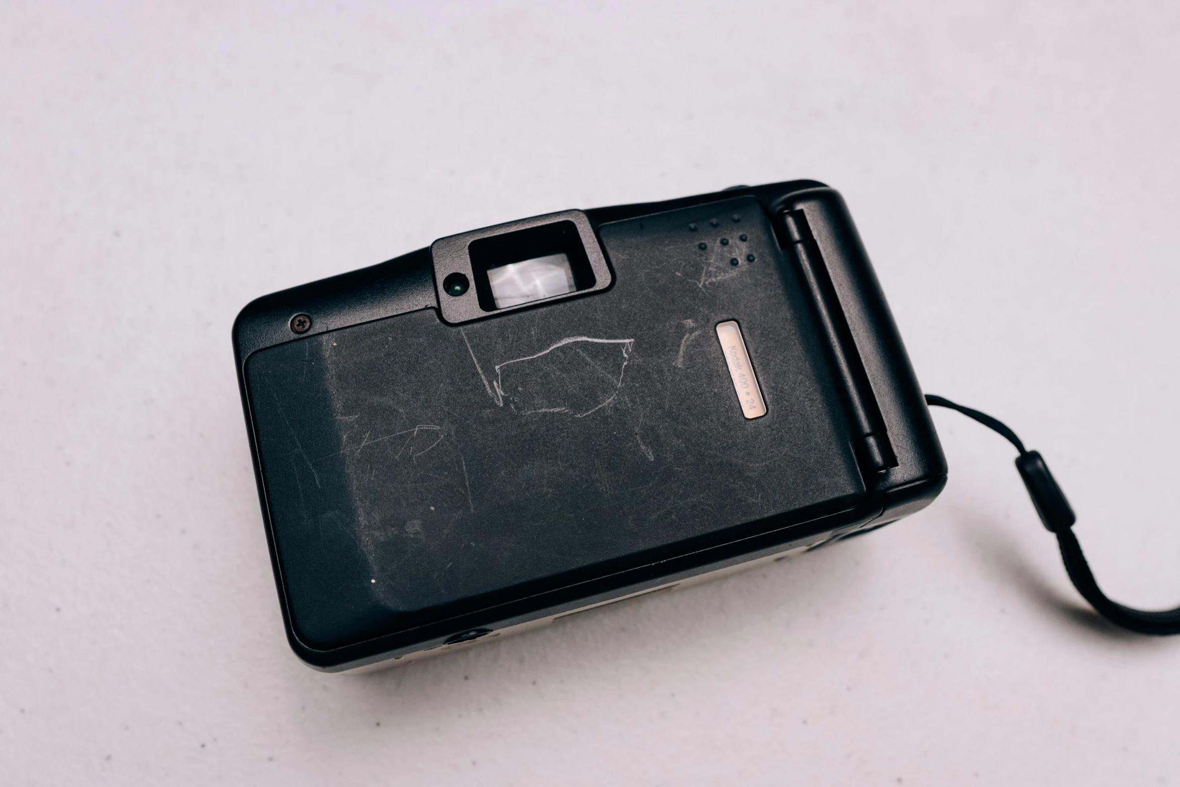 a black camera sitting on top of a white table, by Matthias Stom, unsplash, arte povera, scratches and burns on film, beautiful cameraphone 2000s, taken in the early 1990s, back facing the camera