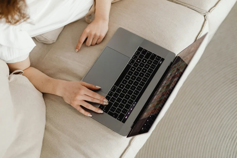 a woman sitting on a couch using a laptop computer, pexels, high angle, apple design, thumbnail, grey