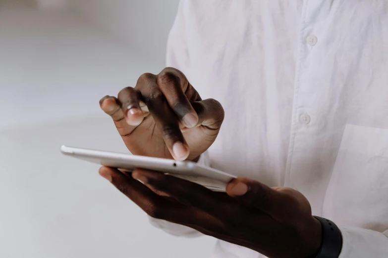 a close up of a person holding a tablet, by Carey Morris, trending on pexels, happening, man is with black skin, wearing a white button up shirt, accurate fingers, mobile game