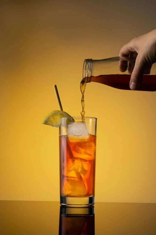 a hand is pouring liquid into a drink