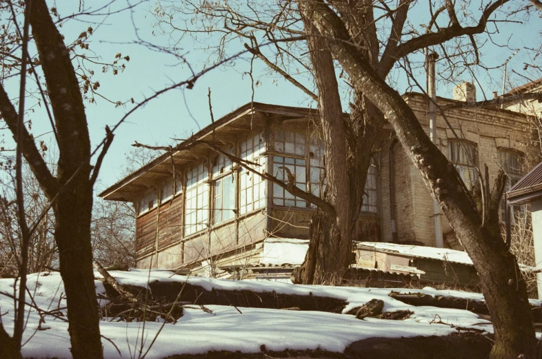 a house sitting on top of a snow covered hill, an album cover, inspired by Isaac Levitan, unsplash, bauhaus, abandoned laboratory, vintage color photo, brown, julia gorokhova