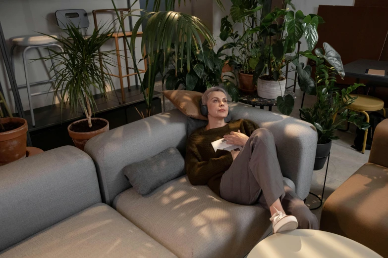 a woman sitting on a couch in a living room, inspired by Peter de Sève, pexels contest winner, lush foliage, 3d feeling, cinematic full body shot, connectivity