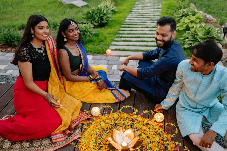 a group of people sitting around a fire pit, a portrait, pexels contest winner, hurufiyya, hindu ornaments, lights with bloom, avatar image, promotional photo