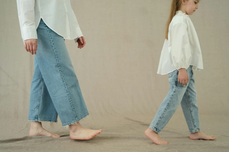 a little girl standing next to an adult walking along side