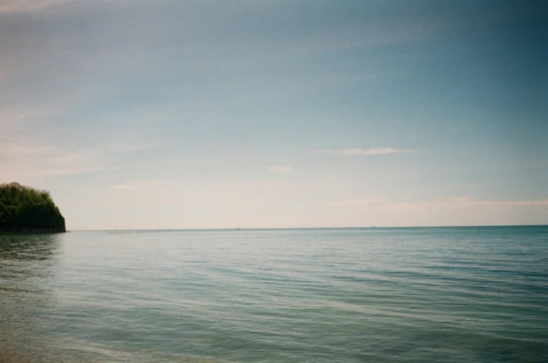 a man riding a surfboard on top of a sandy beach, unsplash, minimalism, muted color (blues, great barrier reef, photo taken on fujifilm superia, looking towards the horizon