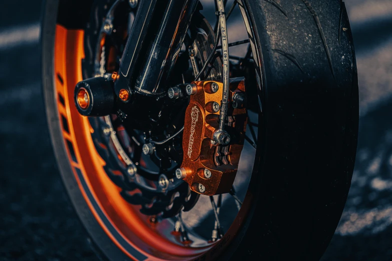 a close up of the front wheel of a motorcycle, by Thomas Häfner, pexels contest winner, hyperrealism, orange metal ears, with glow on some of its parts, flat colour, wheelie