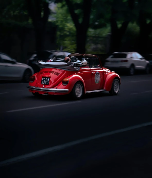 an old red vintage car driving down the road