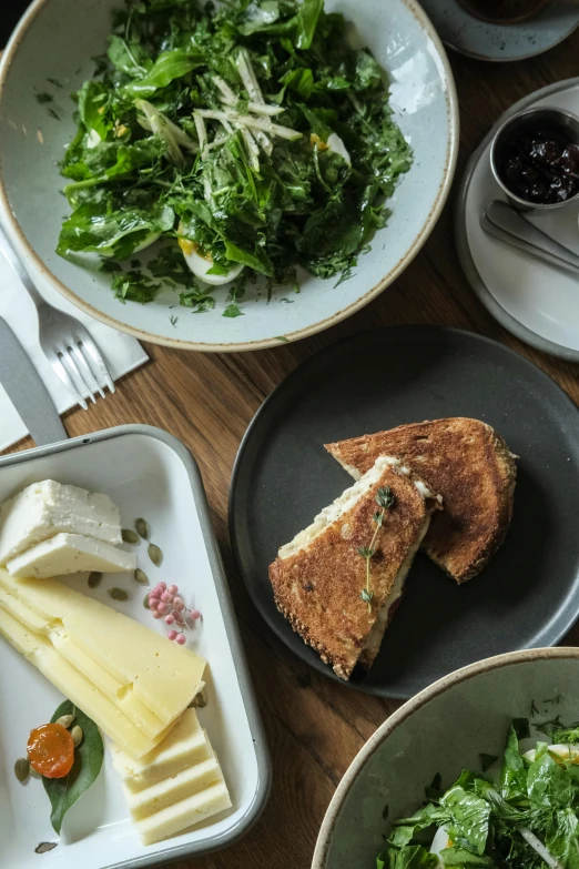 a wooden table topped with plates of food, inspired by Richmond Barthé, unsplash, melted cheese, sandwich, manuka, ca