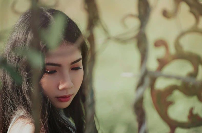 a close up of a person looking at a cell phone, a picture, inspired by Elsa Bleda, trending on pexels, realism, beautiful asian girl, entwined in vines and nature, looking serious, vietnamese woman