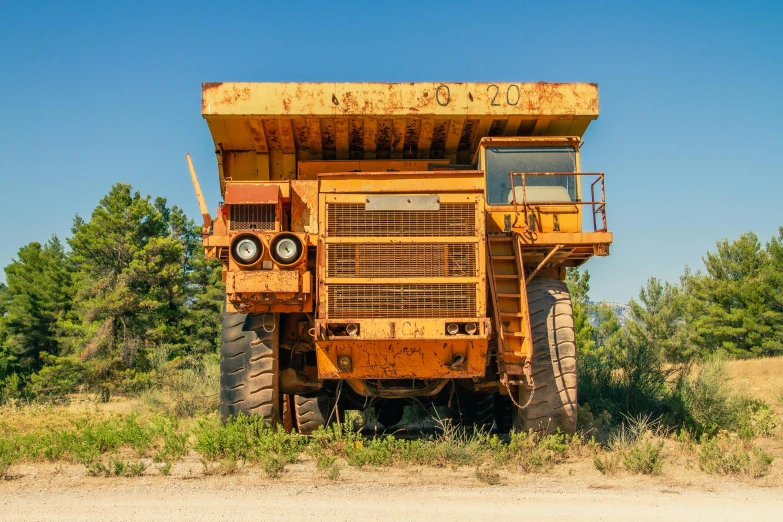 a large yellow dump truck parked on the side of the road, an album cover, unsplash, “ iron bark, front view 2 0 0 0, hillbilly, mechanical superstructure