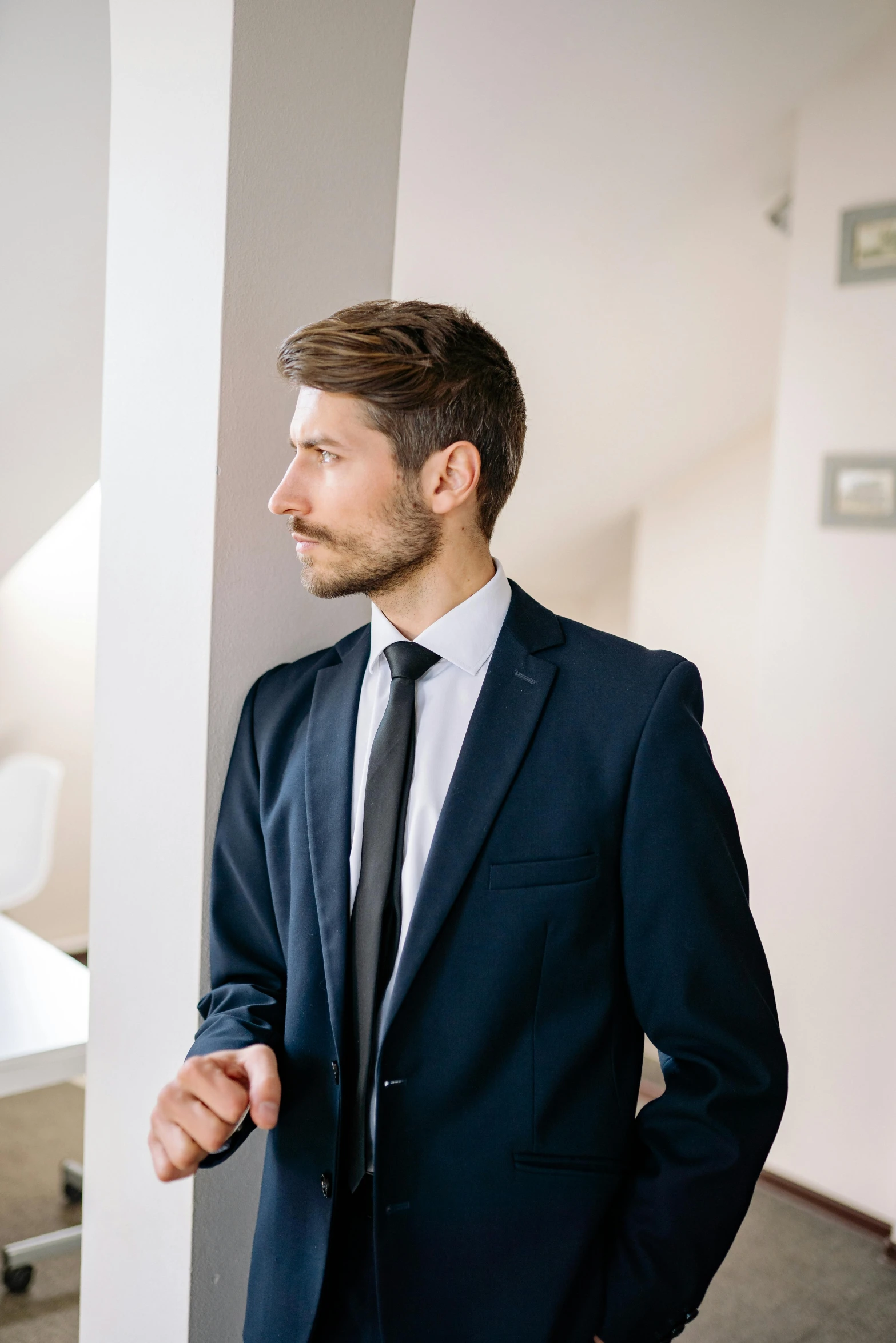 a man in a suit stands near a pillar