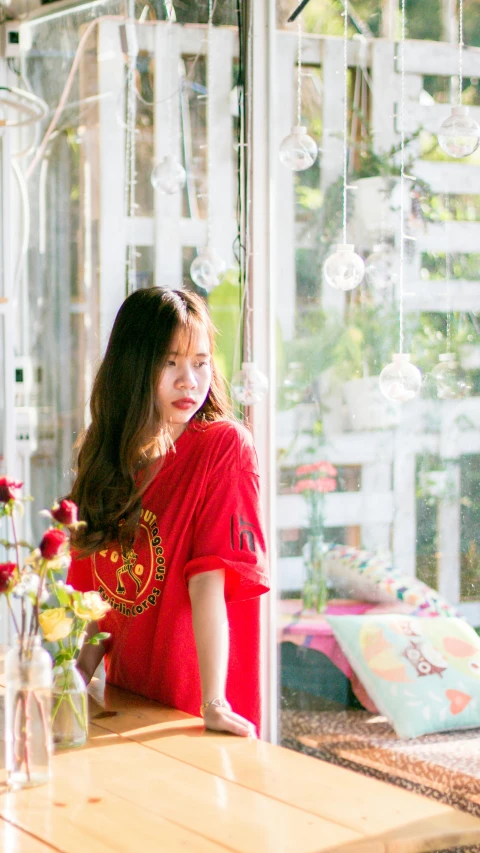 a woman in a red shirt sitting at a table, inspired by Cui Bai, pexels contest winner, standing near a window, profile image, ulzzang, large)}]
