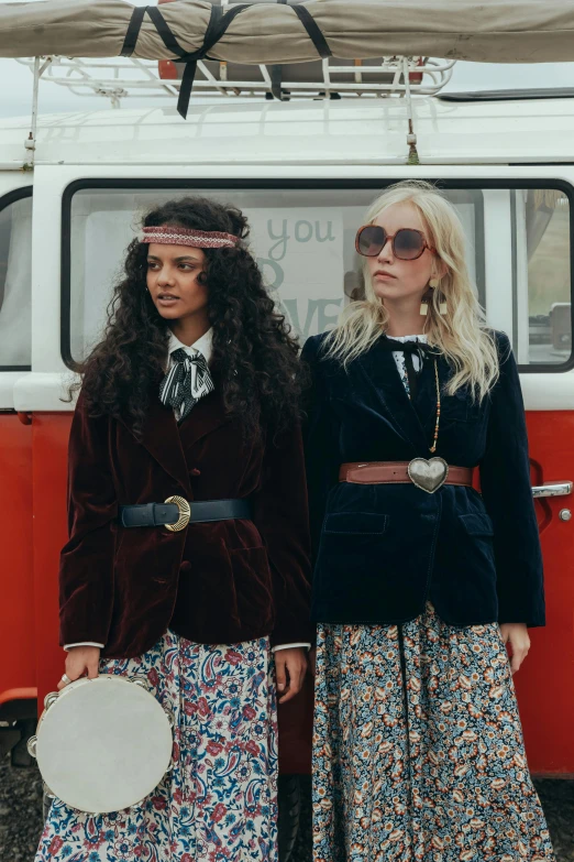 two women standing next to each other in front of a van, by Jemima Blackburn, trending on pexels, renaissance, wes anderson and gucci, velvet frock coat, hippie and boho fashion 1970s, diverse costumes