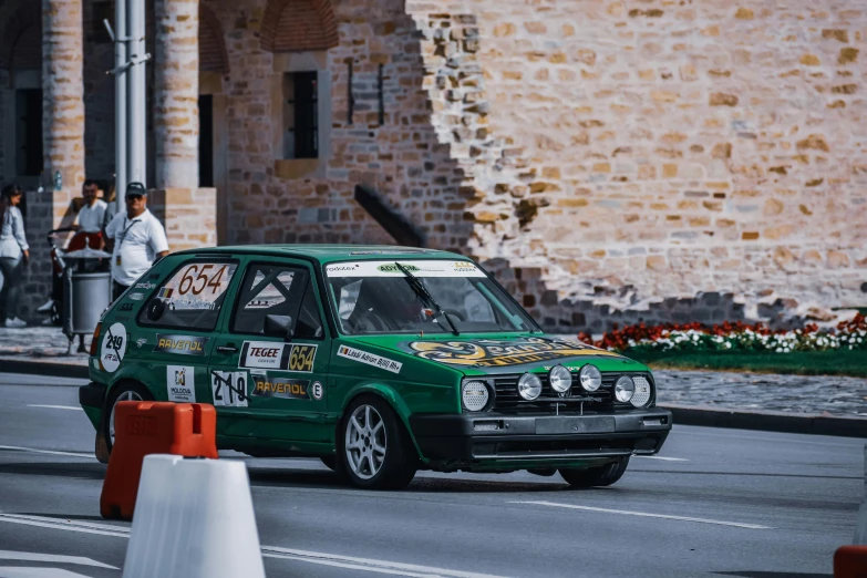 a small green car driving down a street, pexels contest winner, renaissance, rally car, historical setting, podium, bulli