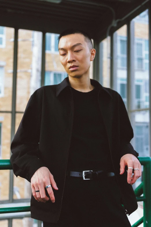 a man standing in front of a green railing, an album cover, inspired by Xia Chang, trending on unsplash, portrait androgynous girl, casual black clothing, a portrait of issey miyake, asian human