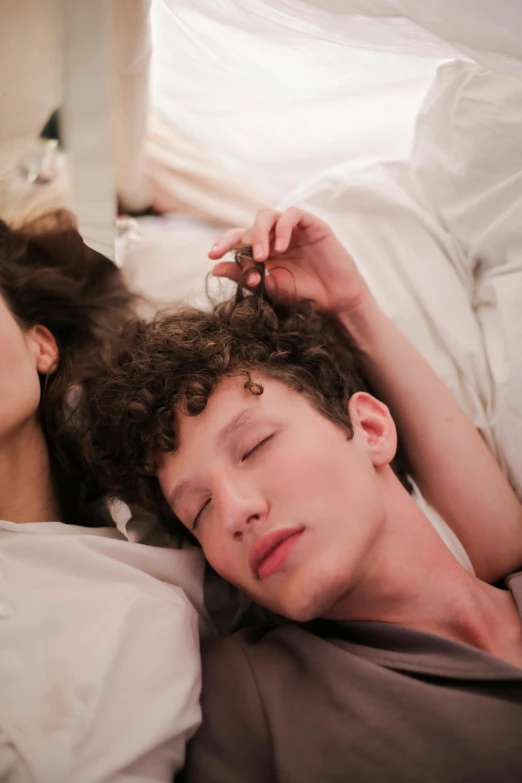 a man and a woman laying in bed next to each other, inspired by Nan Goldin, trending on pexels, renaissance, finn wolfhard, curls on top of his head, bella hadid, long neck
