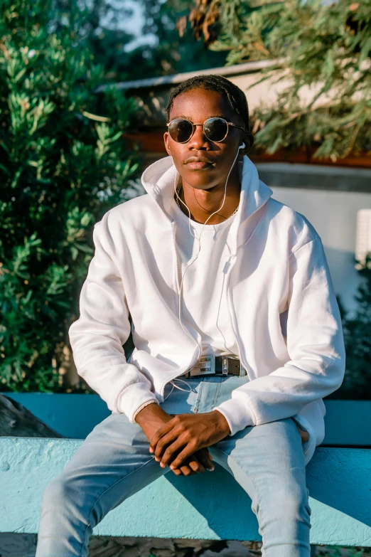 a black man wearing sunglasses is sitting on a bench