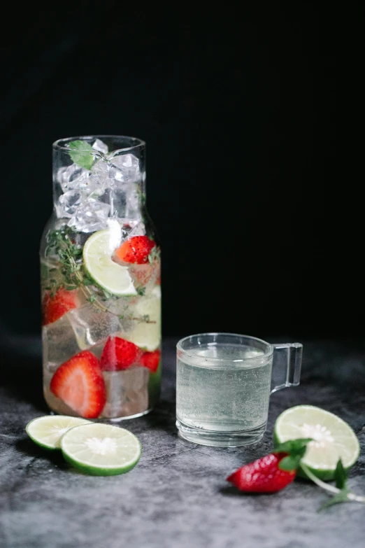 some strawberries and lime are inside of glass jugs