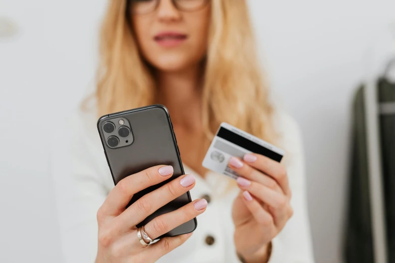 woman holding up a cell phone and credit card