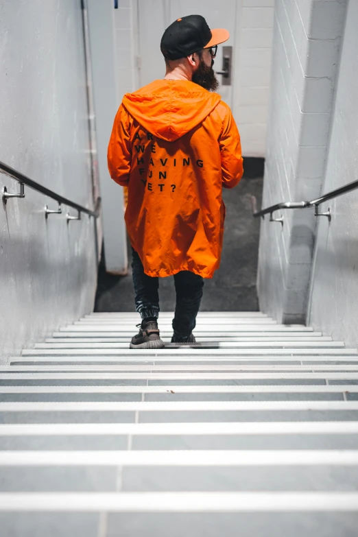 a man in an orange jacket walking up a flight of stairs, inspired by Christo, pexels contest winner, graffiti, wearing a dark hood, yung lean, exiting from a wardrobe, single color