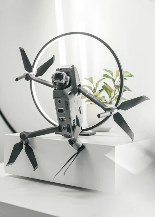 a small drone sitting on top of a white box, inspired by Robert Zünd, pexels contest winner, kinetic art, holding a pair of fans. unreal 5, ornamental halo, air support, placed in a living room