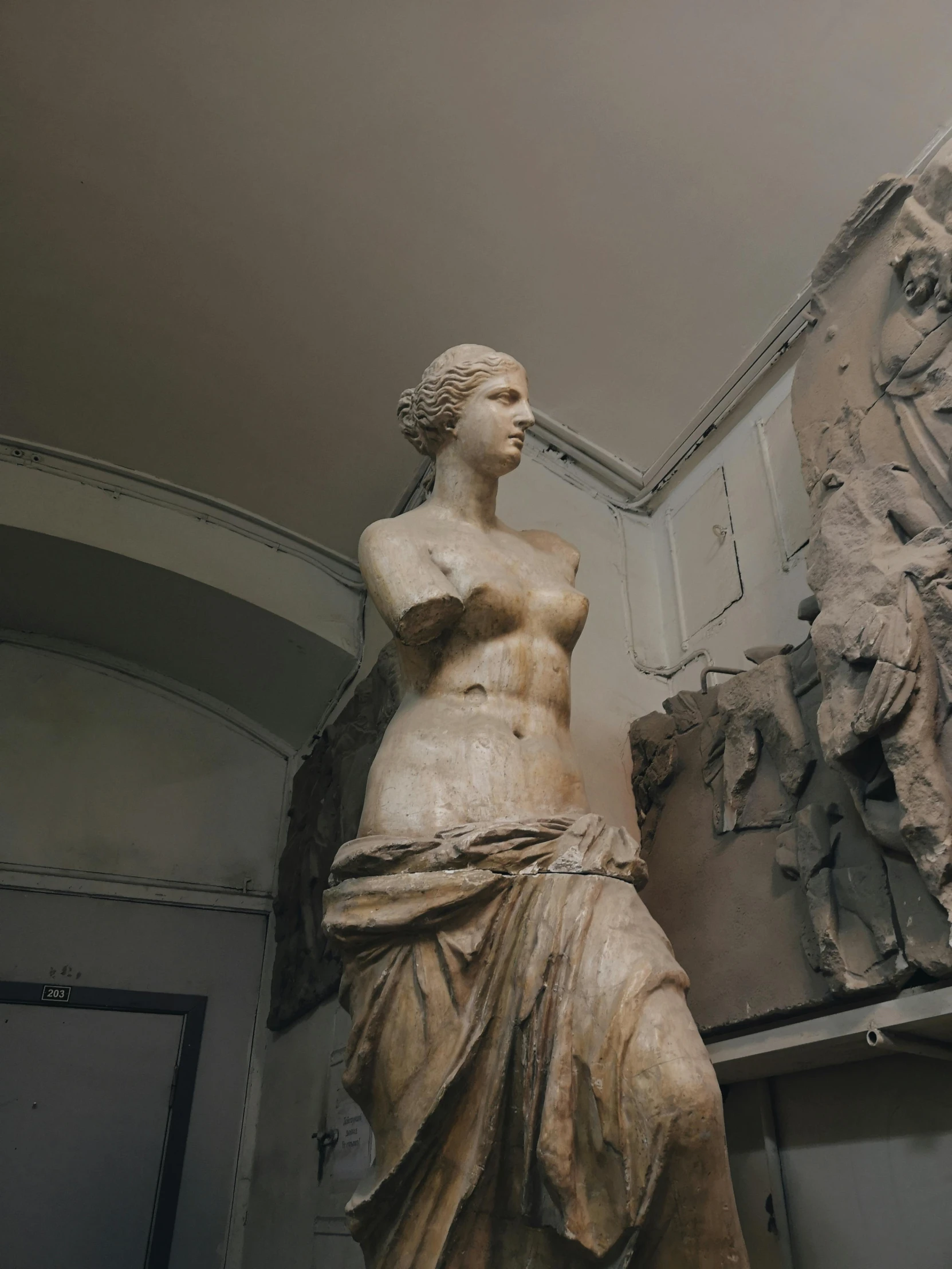 a statue of a woman standing next to a mirror, a statue, inspired by Antonio Canova, pexels contest winner, mannerism, venus de milo with arms, [sculpture] and [hyperrealism], inside building, grey