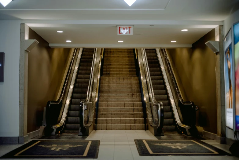 the escalator on the top floor is empty with a person walking down it