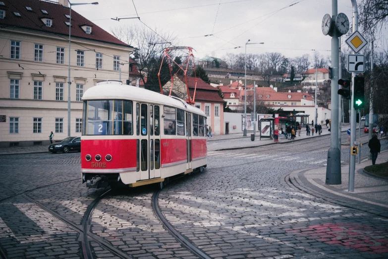 a red and white trolley traveling down a street, by Tobias Stimmer, pexels contest winner, square, prague, 1990s photograph, brown