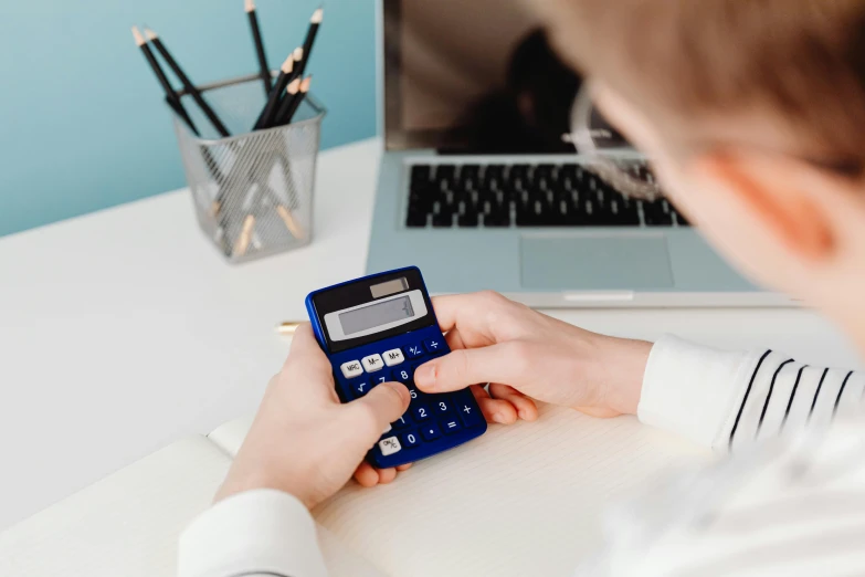 a person using a calculator in front of a laptop, trending on pexels, avatar image, cutest, wētā fx, lachlan bailey