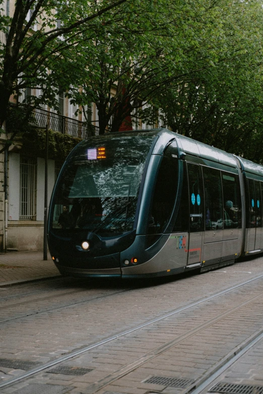 a long modern city train on tracks near a building