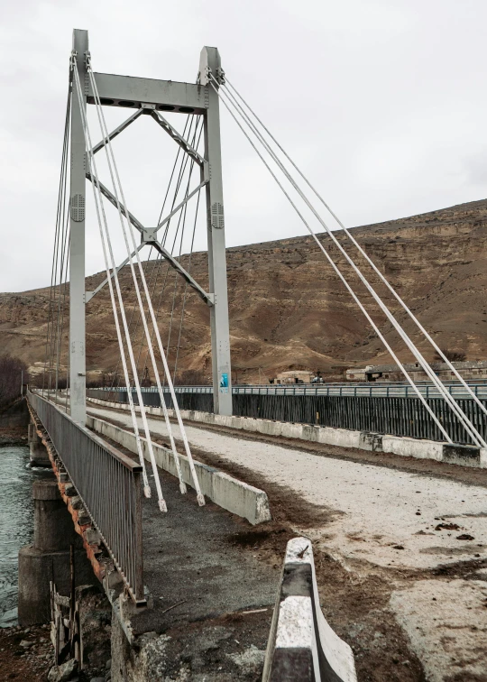 a bridge over a body of water with a mountain in the background, hurufiyya, with cables and wires coming out, 2022 photograph, idaho, kurdistan