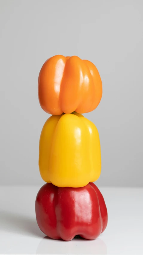 a stack of peppers sitting on top of each other, inspired by Sarah Lucas, new sculpture, red+yellow colours, zoomed out shot, asset on grey background, pumpkin