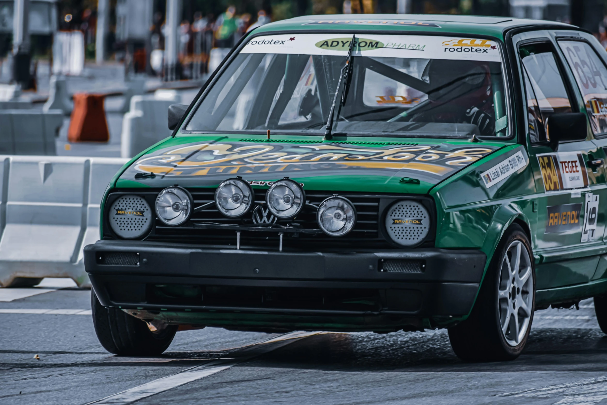 a green car driving down a city street, by Carlo Martini, pexels contest winner, photorealism, rally car, front face, turbo, in sao paulo