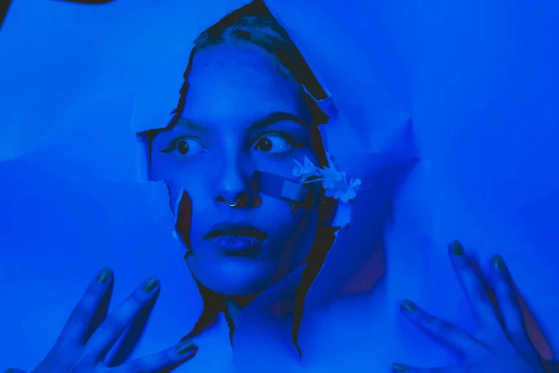 a woman with blue paint on her face, an album cover, inspired by Elsa Bleda, pexels contest winner, video art, anya_taylor-joy, cut-out paper collage, uv blacklight, emerging from her lamp