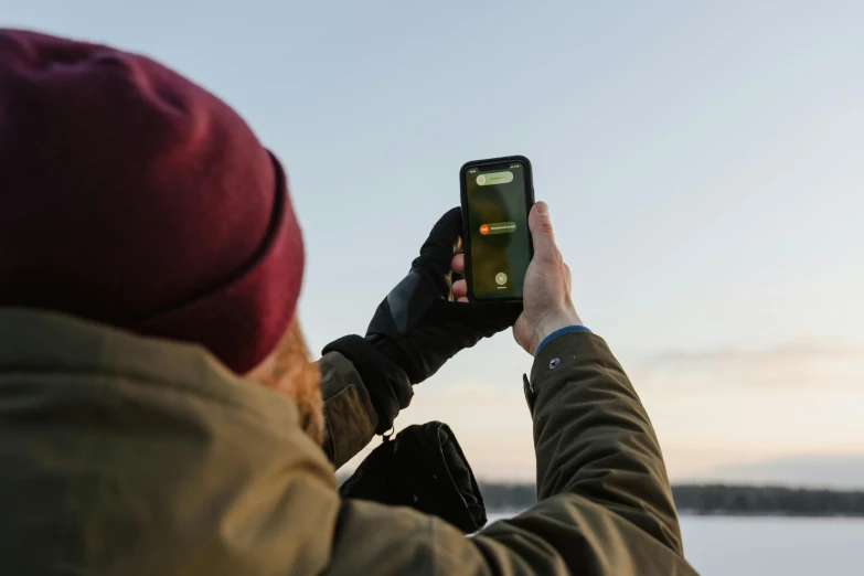 a person taking a picture of a body of water, flickering, holding a very advance phone, bjørn skalldrasson, guide