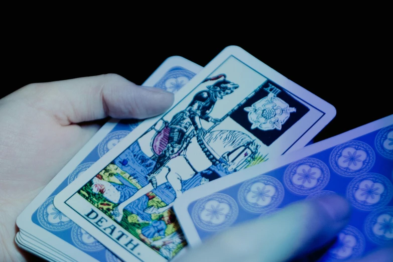 a person holding a deck of cards in their hands, a hologram, inspired by Harry Clarke, unsplash, detail shots, thumbnail, blue - print, death tarot