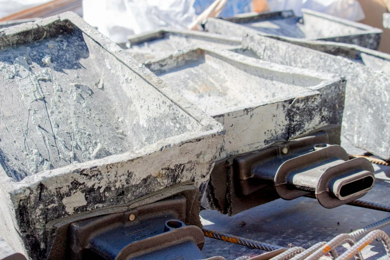 a couple of pieces of metal sitting on top of a pile of concrete, bright construction materials, promo image, up-close, feed troughs