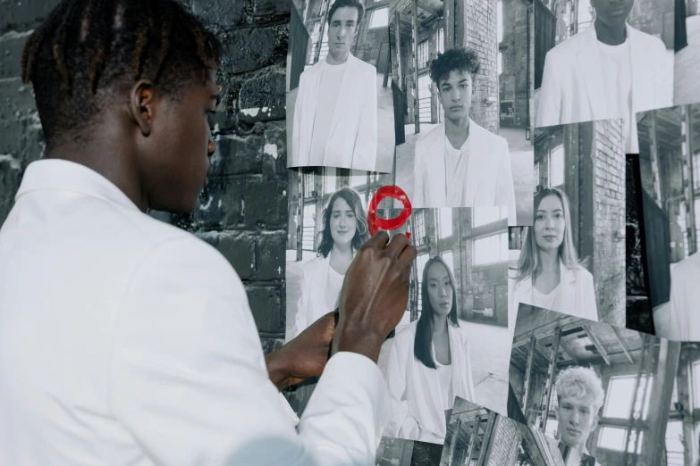 a woman standing in front of a wall covered in pictures, pexels contest winner, hyperrealism, man is with black skin, an all white human, still from a music video, behind the scenes photo