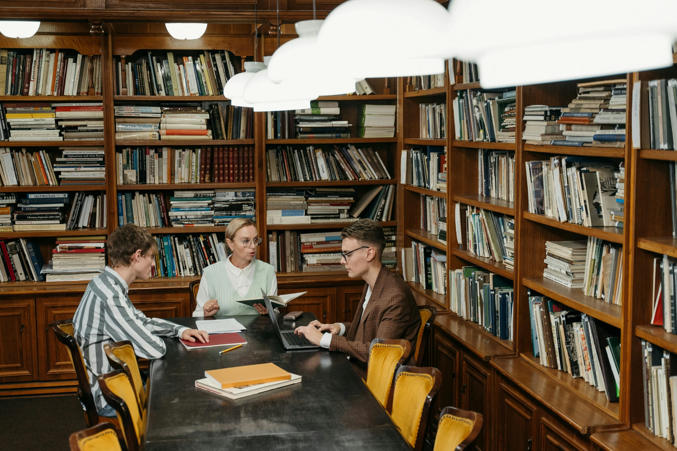 a group of people sitting around a table in a library, kacper niepokolczycki, lachlan bailey, curated collections, thumbnail