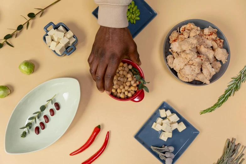 a person holding a bowl of food on a table, a still life, inspired by Ceferí Olivé, unsplash, aardman studios, unmistakably kenyan, on a pale background, cheeses