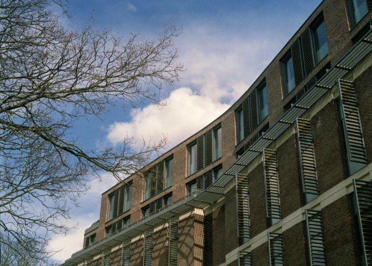 a tall brick building sitting next to a tree, inspired by Peter Zumthor, unsplash, heidelberg school, low dutch angle, brown, delft, exterior view