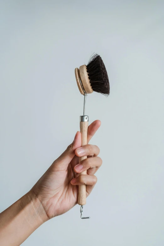 a person is holding up a wooden hair brush