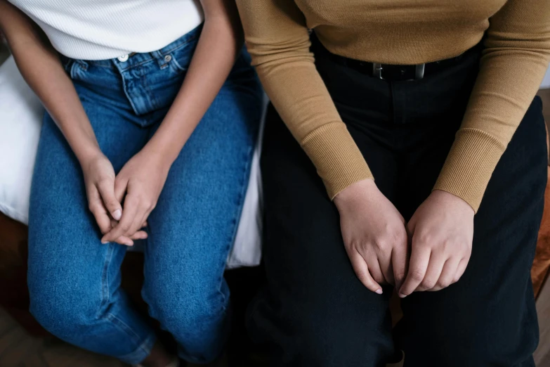 two women sitting together on a chair while they are holding hands