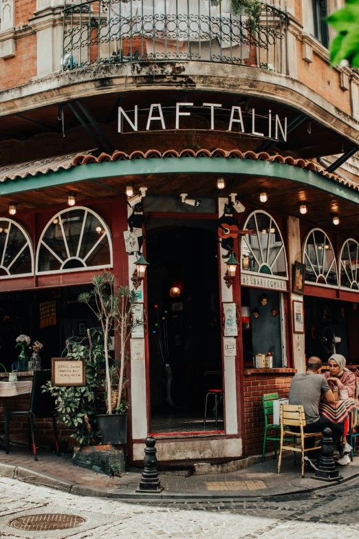 two people sitting at an outside cafe with a table