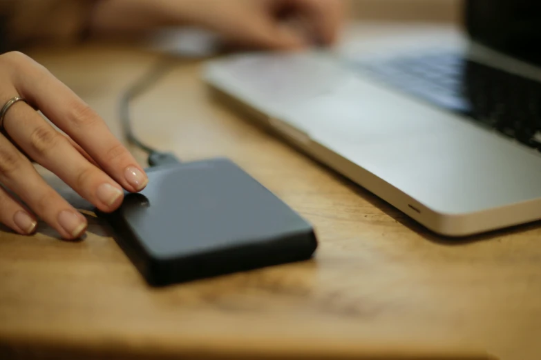 a close up of a person holding a cell phone near a laptop, hdd, thumbnail, digital image, black