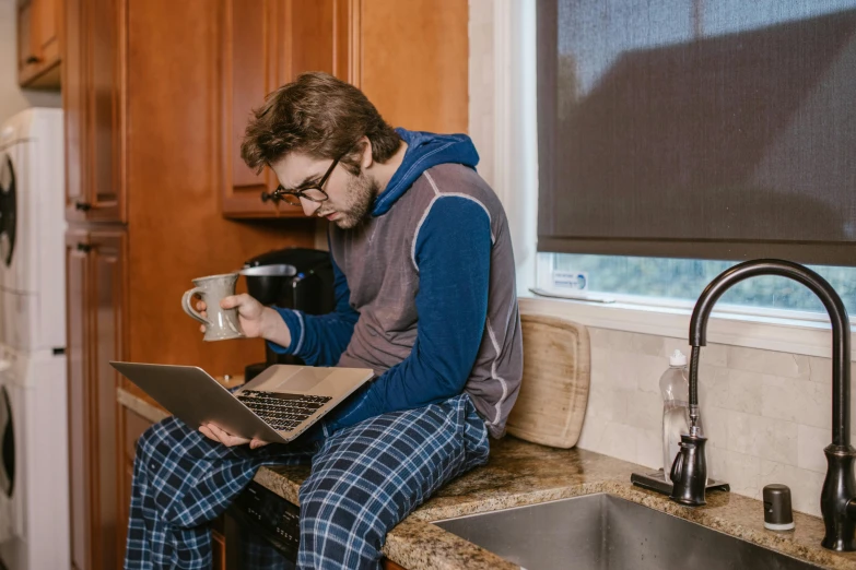 a man sitting on a kitchen counter using a laptop, by Carey Morris, pexels, renaissance, wearing pajamas, avatar image, nerdy, high quality picture