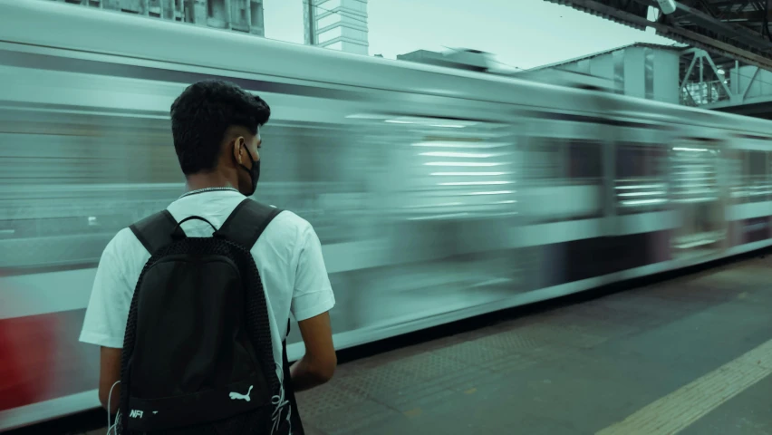 a man with a backpack standing in front of a train, pexels contest winner, profile picture 1024px, pacing, the image is futuristic, urban in background